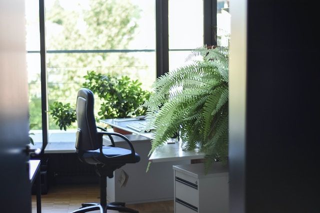 chaise roulante en cuir noir près d’un bureau en bois blanc